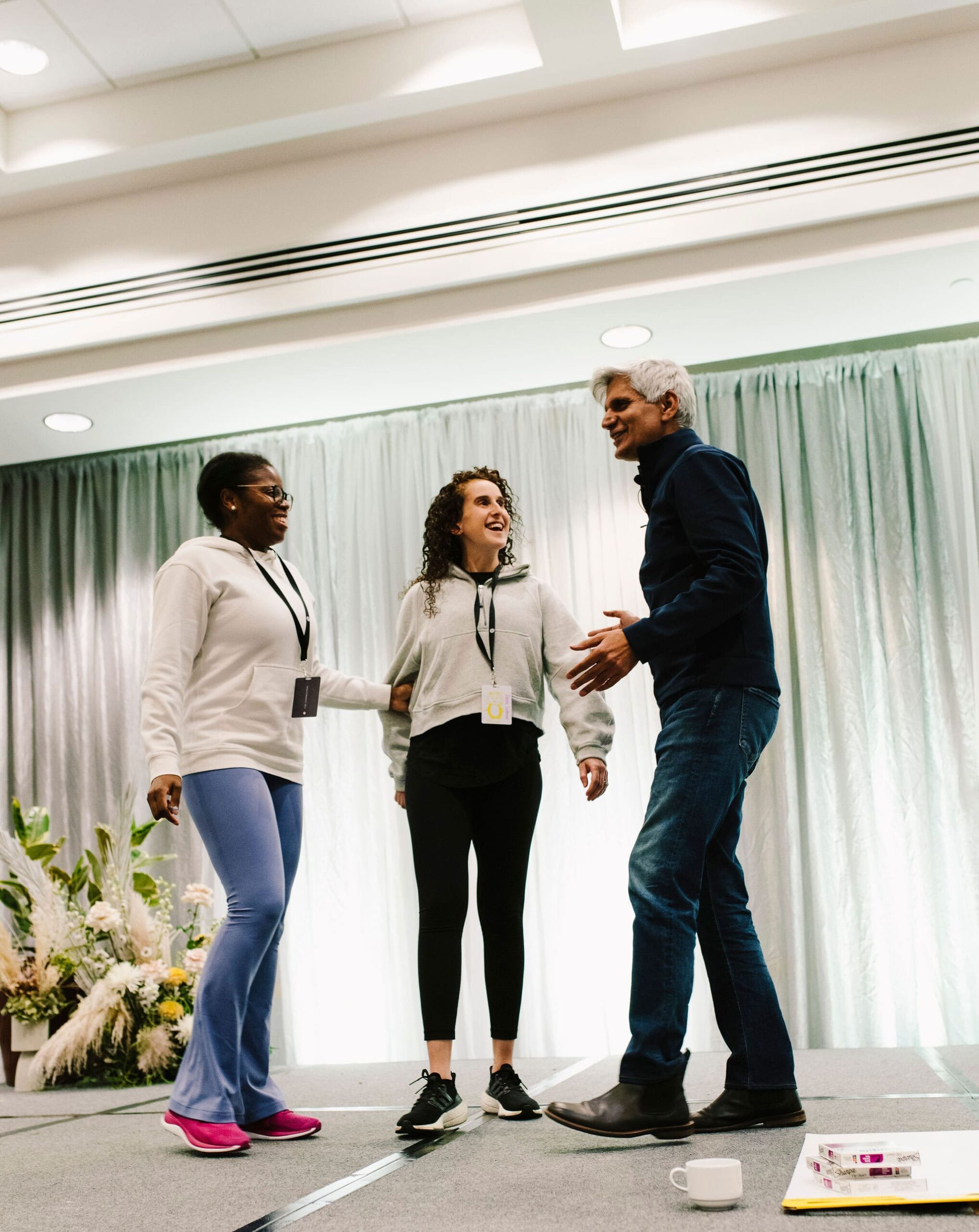 Hitendra Wadhwa smiling and engaging with two participants on stage at Lululemon event