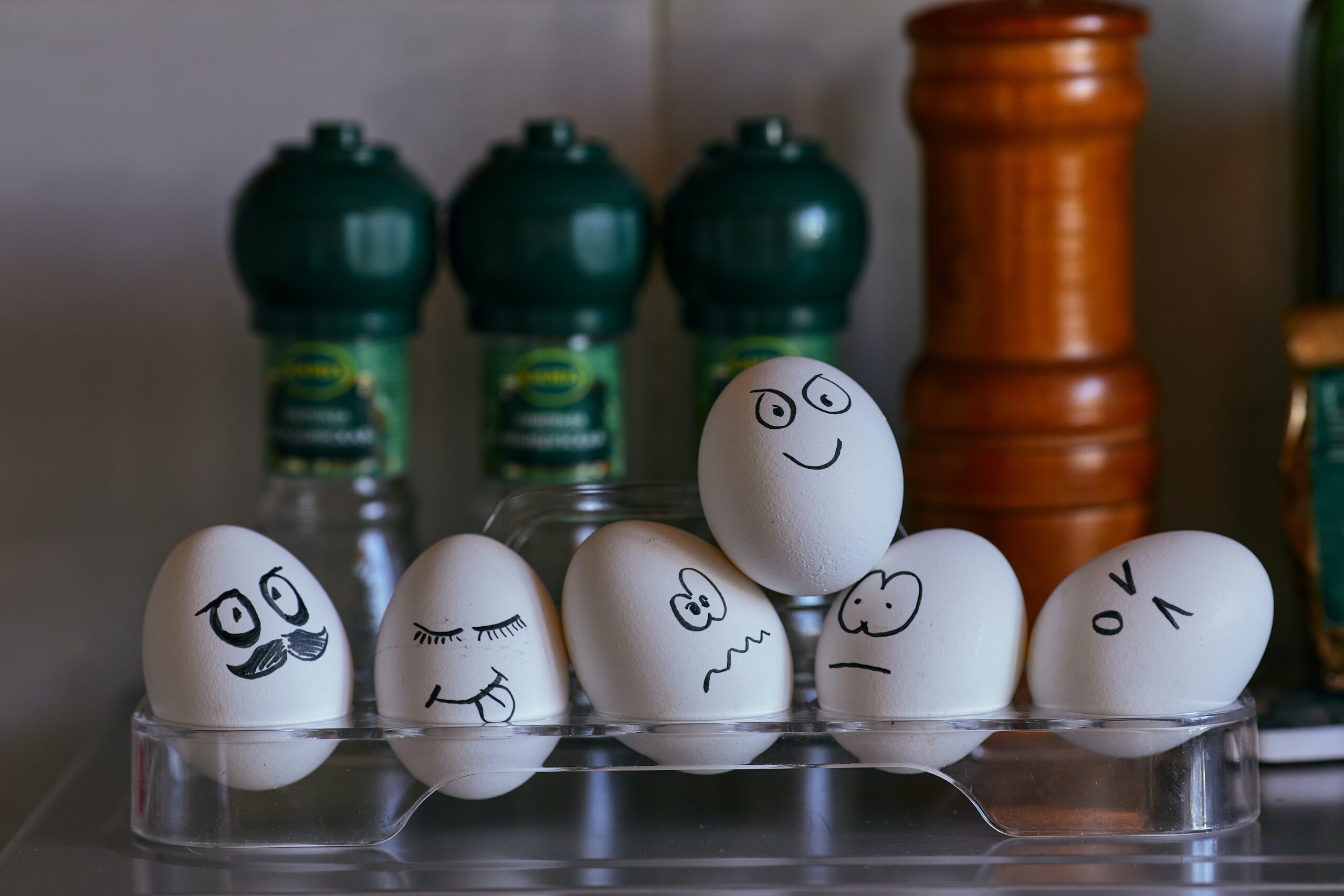 six eggs with different face expression drawn on each arranged in an egg tray.