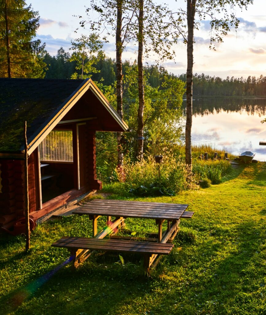 A wooden retreat cottage and picnic table, overlooking a lake