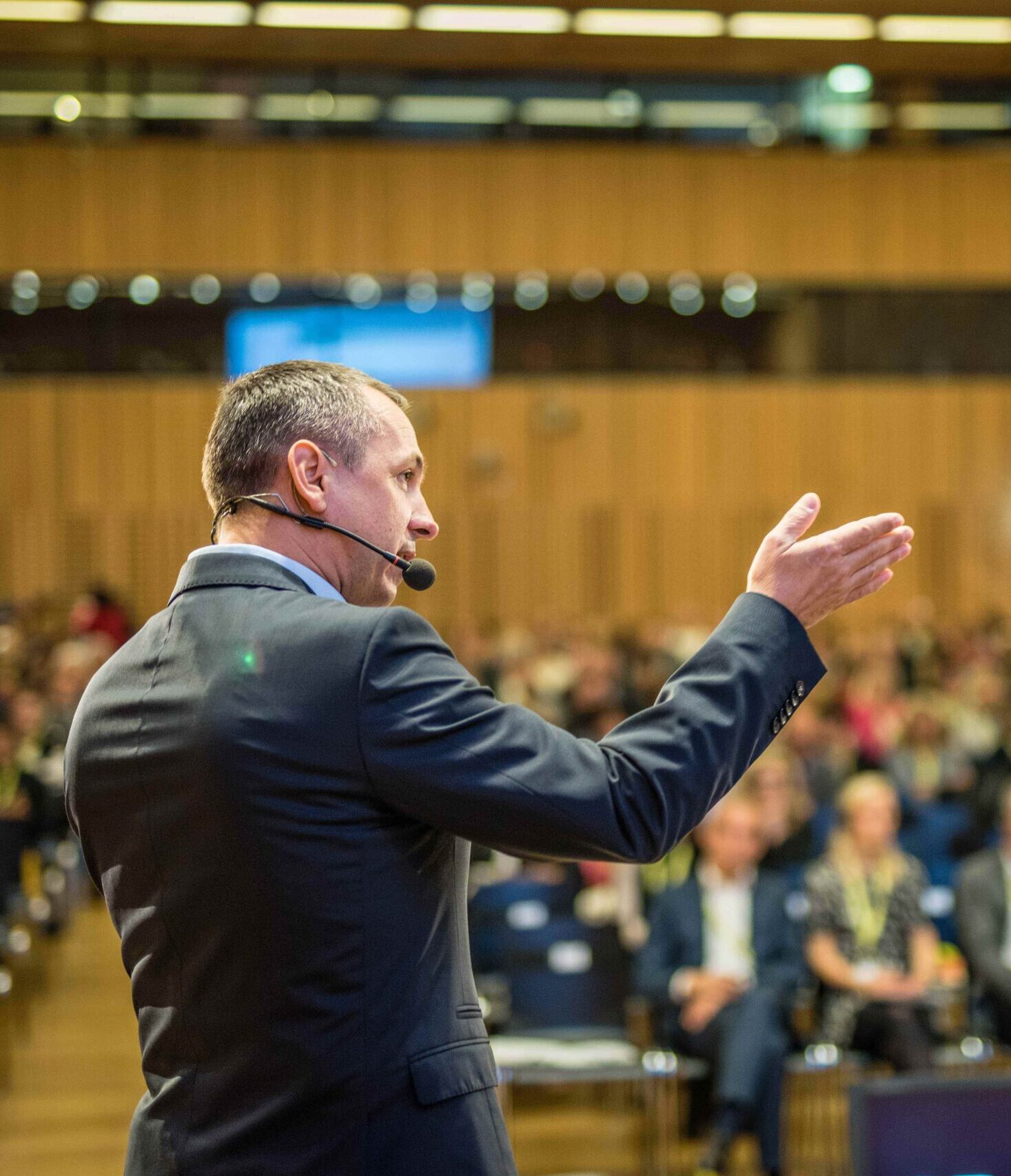 A person speaking on stage, addressing a crowd