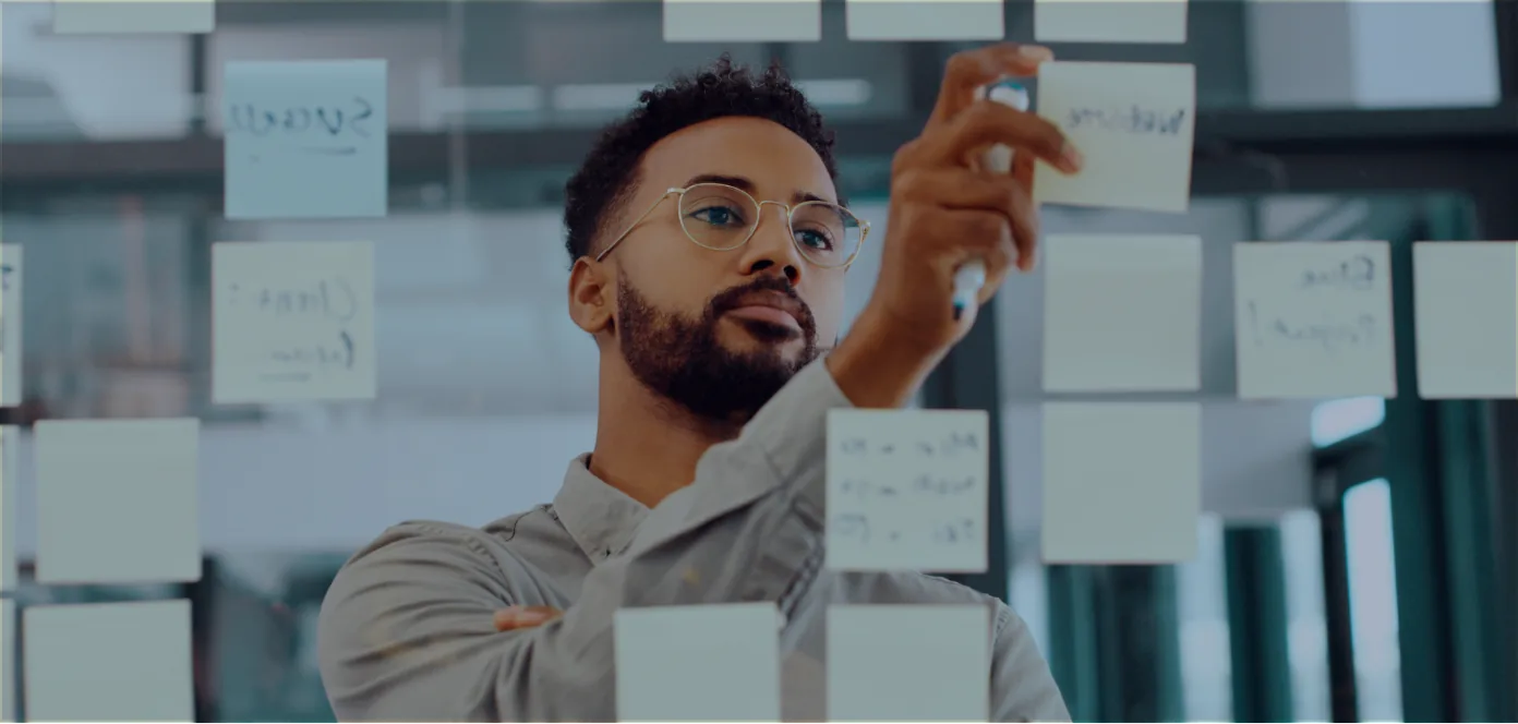 A Mentora Scholar writing on a glass wall covered in sticky notes during a guided virtual session